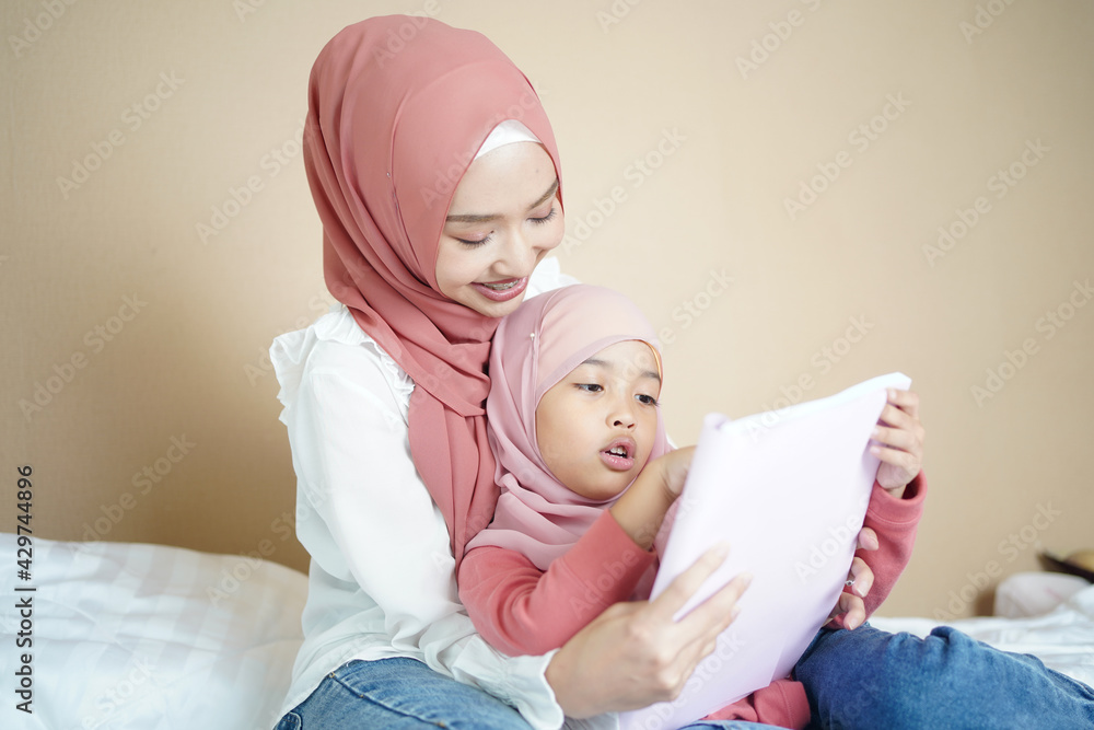 Muslim mother teaching her daughter to read the book. Muslim mother teaching her daughter to read the book.