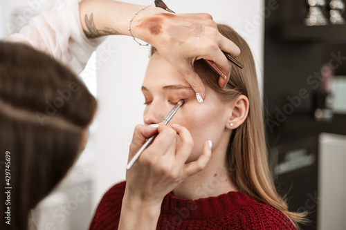 Wallpaper Mural makeup artist applies eye shadow to the eyelids on a beautiful young woman blonde model, face make up concept Torontodigital.ca