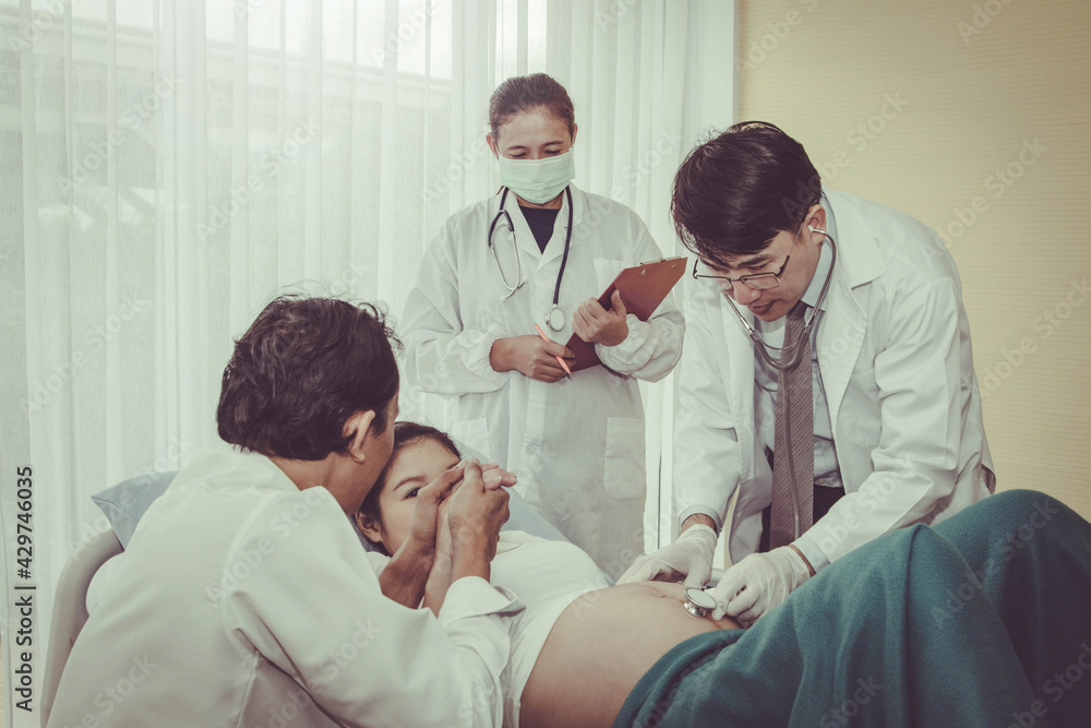 The pregnant woman is near the end of the birth, being well taken care of by the pediatrician's medical team, with her husband having side by side expectations. The pregnant woman is near the end of the birth, being well taken care of by the pediatrician's medical team, with her husband having side by side expectations.