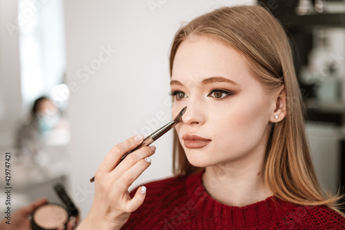 process of face makeup brush alignment of the face tone on a beautiful young woman model blonde