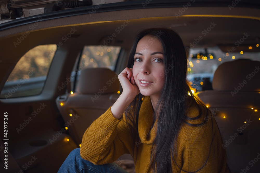 Young beautiful brunette enjoys relaxing in the trunk of her car. Young beautiful brunette enjoys relaxing in the trunk of her car.