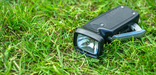 Black mechanical flashlight on the ground in the green grass