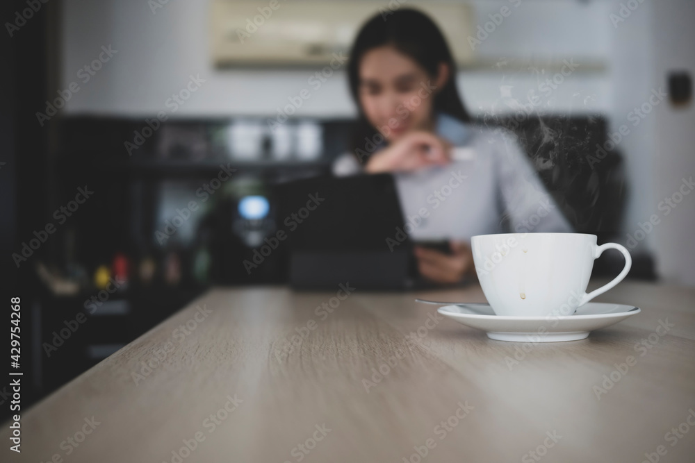 Close up view of white coffee cup on wooden table with businesswoman in background. Close up view of white coffee cup on wooden table with businesswoman in background.