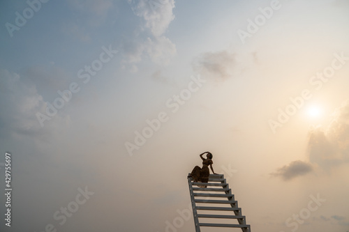 Woman in brown dress sitting on the staircase, sunset moment.