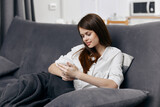 happy woman sitting on the couch with a phone in her hands interior comfort