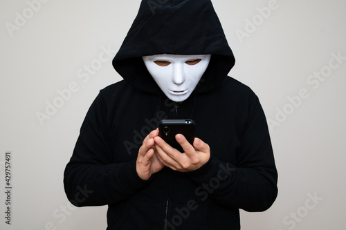 Hacker with anonymous mask holding his phone