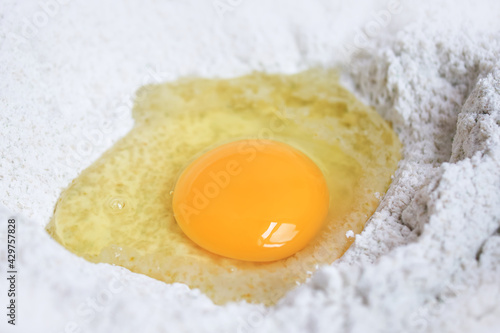 Raw egg yolk on whole wheat flour mixing grains, Preparation homemade ingredients dough used to make bakery, Pastry, Bread, Pasta, Noodles and Dumpling.