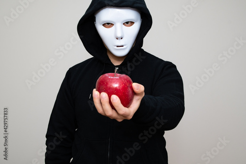 Hacker with anonymous mask holding an apple with his left hand