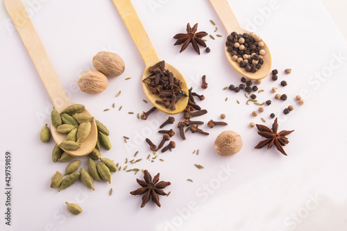 Wooden spoons with cloves  cardamom  and black peppercorns top view stock photo