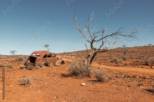The rusted abandoned wreck of an old car in a remote area of Australian Outback on a rural dirt road near Fowlers Gap, NSW