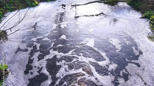 Brown swamp water full of organic substances flows down the pipe and forms a plentiful foam, biofouling photo