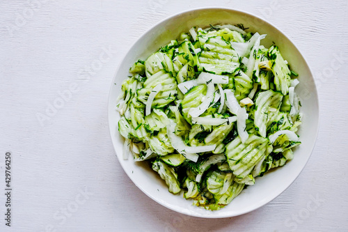 Homemade sauerkraut salad of sliced cucumbers in a bowl on a gray background. Fermented vegetables. Vegetarian vegan food. Healthy food, seasonal preservation of vegetables. Top view. Copy space.