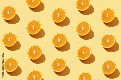 Modern pattern with orange slices on yellow background illuminated by bright summer sunlight - Pop art design minimal creative concept - Fresh fruits top view