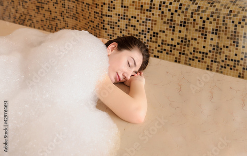 young woman in white foam relaxing in a hamam