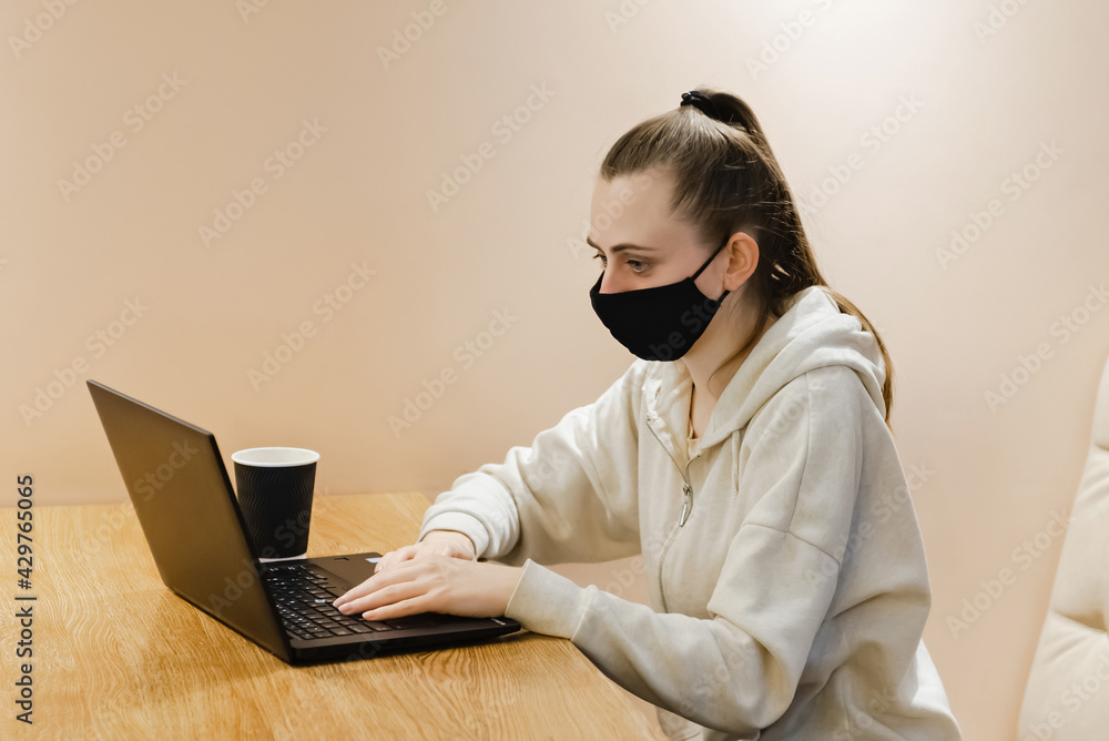 young girl in medical mask work on laptop in cafe young girl in medical mask work on laptop in cafe