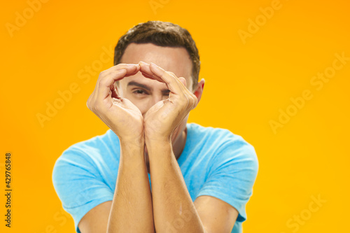 emotional man in blue t-shirt gesturing with his hands yellow background studio