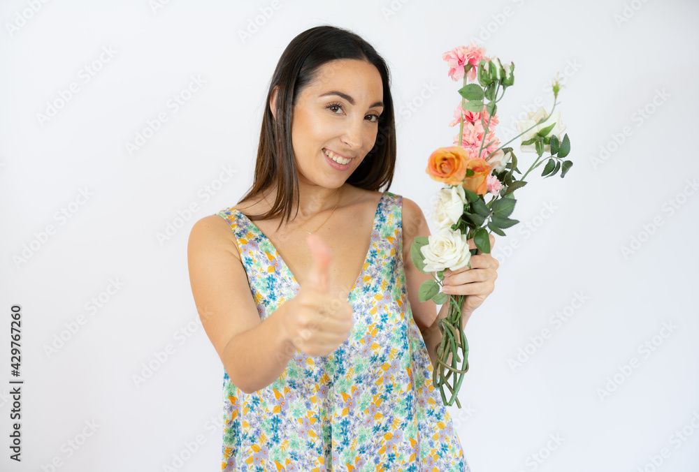 Beautiful woman holding bouquet of flowers with thumb up over white background Beautiful woman holding bouquet of flowers with thumb up over white background