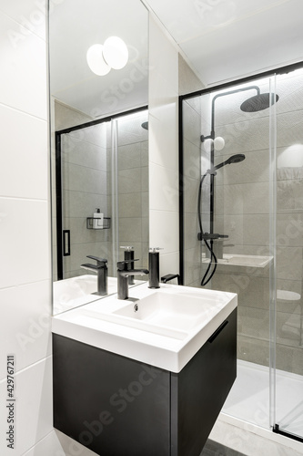 Clean bright bathroom interior with black matte faucet and shower. Original designed space with modern pieces and furniture