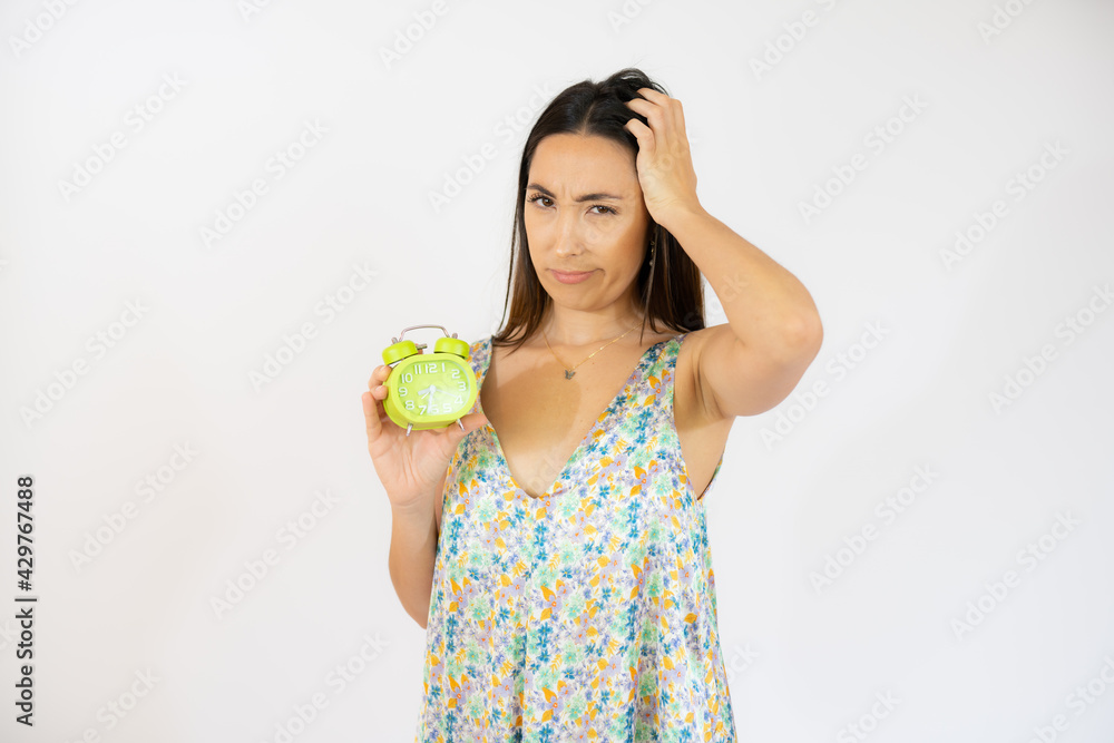 Portrait of pensive young woman holding alarm clock isolated over white background Portrait of pensive young woman holding alarm clock isolated over white background