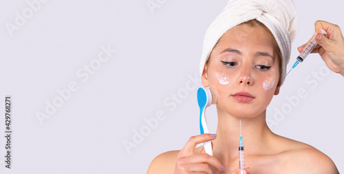Banner, long format over gray background. Felling clean and fresh. Skin care, spa, beauty treatment concept. Woman with facial mask and exfoliation brush, towel on head looking skeptical to injections photo