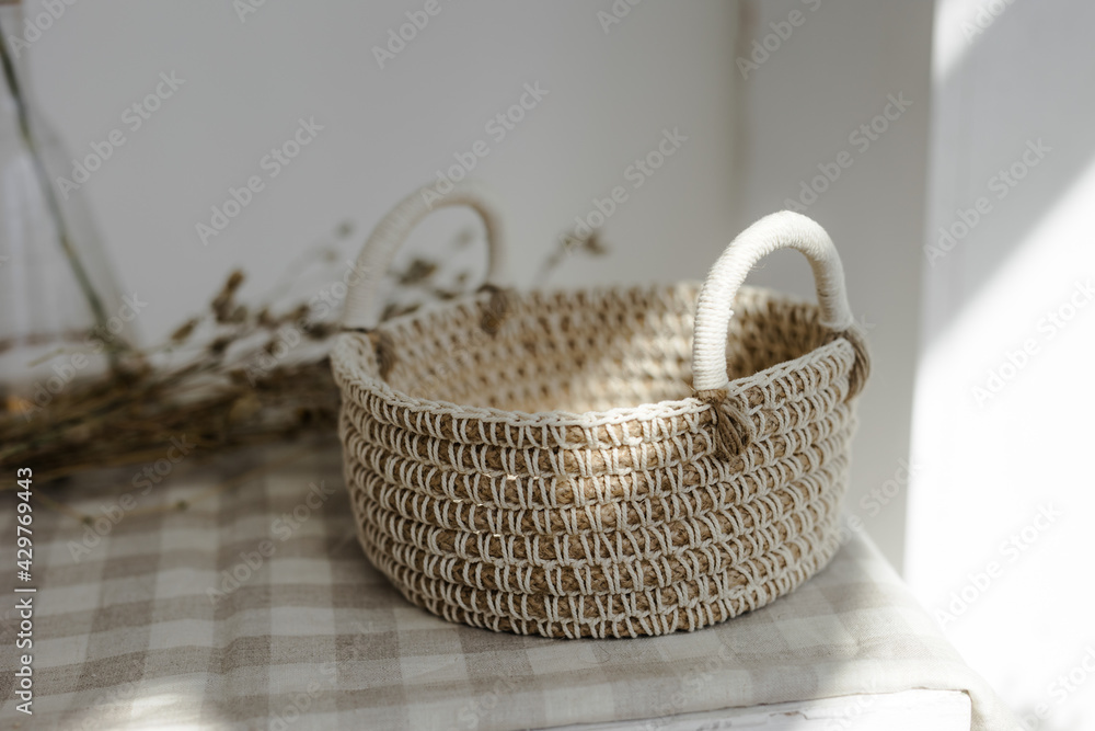 Handmade home decor made from organic jute fiber. a wicker jute basket with handles is placed on a checkered linen napkin. the concept of home decor and comfort in the eco style.