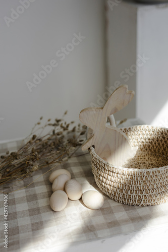 Handmade home decor made from organic jute fiber. Round wicker jute basket with handles on a cotton napkin. wooden eggs next to the basket. wooden figure of a rabbit in a basket. The concept of Easter