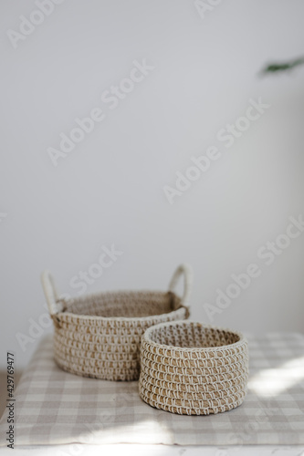 Handmade home decor made from organic jute fiber. Two wicker jute baskets are arranged on a checkered linen napkin. The concept of Easter decor.