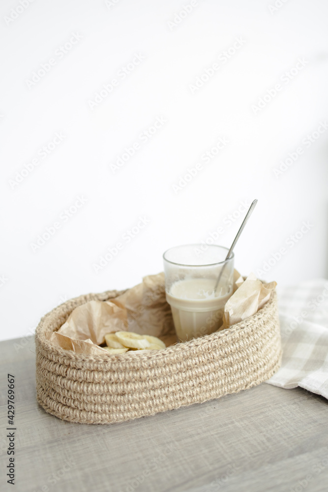 Handmade home decor. oval jute basket with wooden bottom, tray, food stand, table setting. the concept of home decor and comfort in the eco style. a rice cake with a banana and a clear glass of latte. Handmade home decor. oval jute basket with wooden bottom, tray, food stand, table setting. the concept of home decor and comfort in the eco style. a rice cake with a banana and a clear glass of latte.