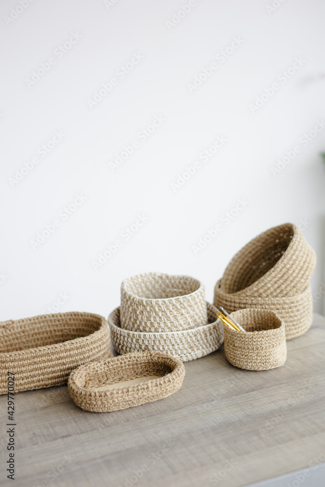 Handmade home decor made from organic jute fiber. many jute baskets of different sizes are arranged on a wooden table. room white background