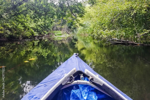 The blue nose of a kayak on the background of a river in the middle of the forest.Extreme kayaking. Concept: water sports, adrenaline, kayaking, adventure.