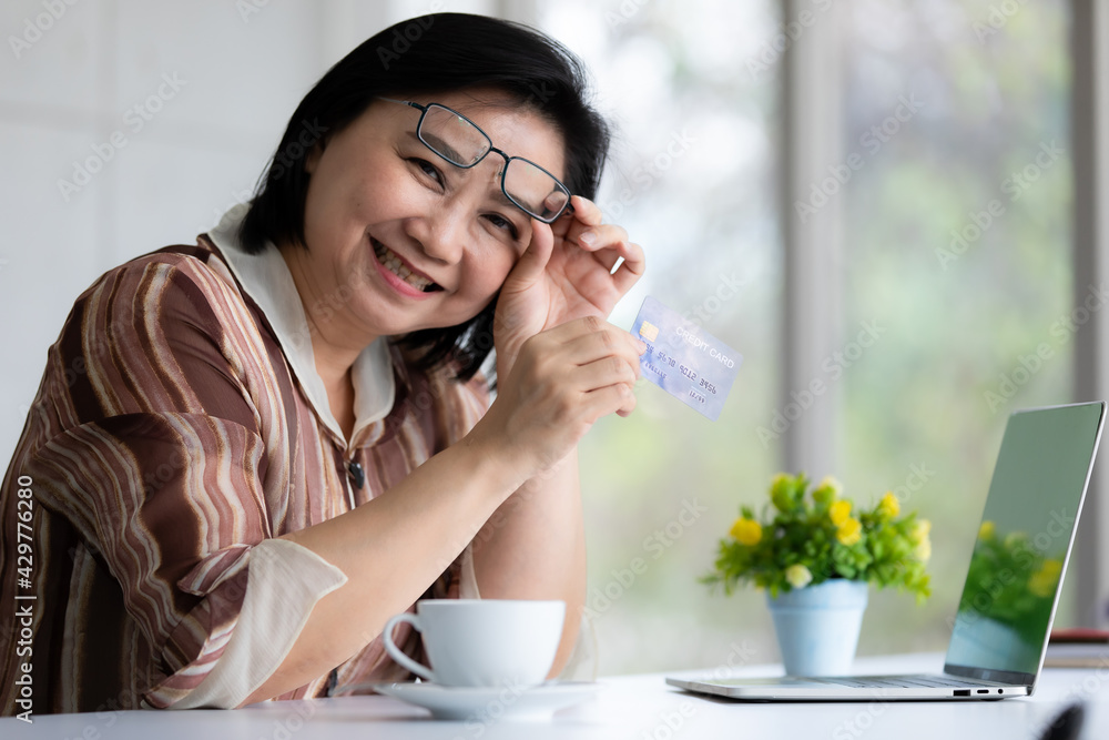 Asian woman holding credit card and smile with happy face while online shopping via notebook computer. Asian woman holding credit card and smile with happy face while online shopping via notebook computer.