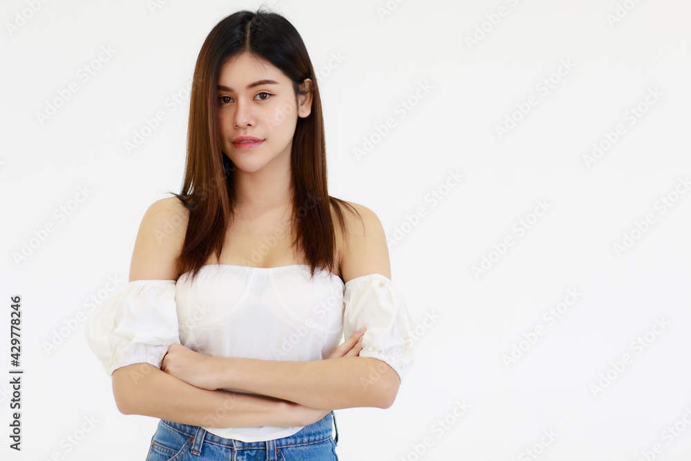 Portrait An Asian adult woman looks teenage-style with her long hair and black color smiling standing and looking at a camera. A woman wears a white shirt and blue jean with white background. Portrait An Asian adult woman looks teenage-style with her long hair and black color smiling standing and looking at a camera. A woman wears a white shirt and blue jean with white background.