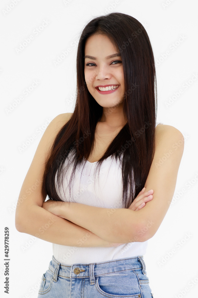 Portrait of One Asian adult woman with long black hair standing, smiling and looking at a camera with hands in blue jean. Woman wear a white camisole and jeans shoot with white background in a Studio Portrait of One Asian adult woman with long black hair standing, smiling and looking at a camera with hands in blue jean. Woman wear a white camisole and jeans shoot with white background in a Studio