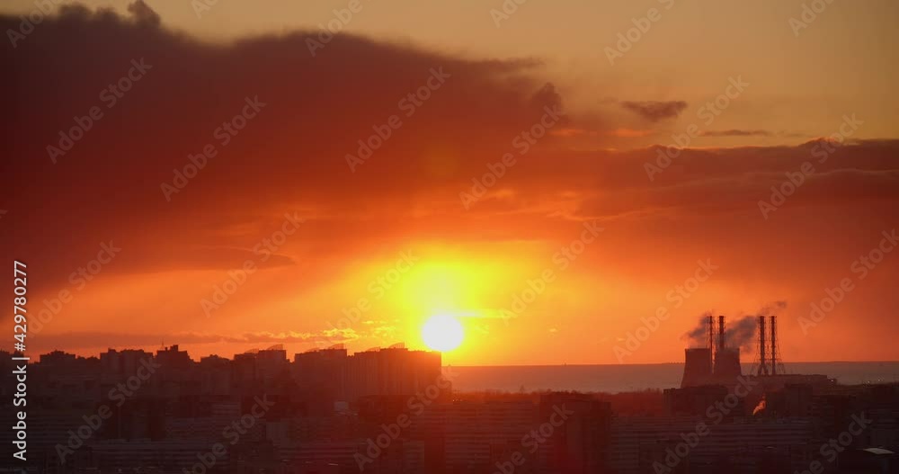 Time lapse of a sunset in the city. The sun sets over the horizon against the backdrop of city buildings, the sea and a thermal power plant. Time lapse of a sunset in the city. The sun sets over the horizon against the backdrop of city buildings, the sea and a thermal power plant.