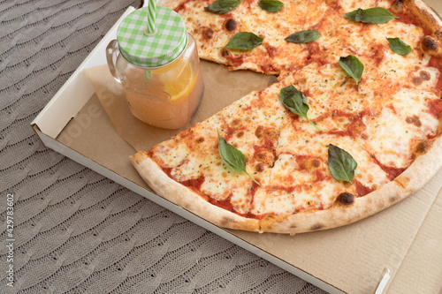 Take away Pizza margarita with bazilic in carton box and lemonade photo