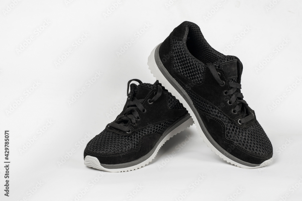 Sneakers for boys or girls, unisex, on a light background. Sporty black sneakers with a light comfortable sole Sneakers for boys or girls, unisex, on a light background. Sporty black sneakers with a light comfortable sole