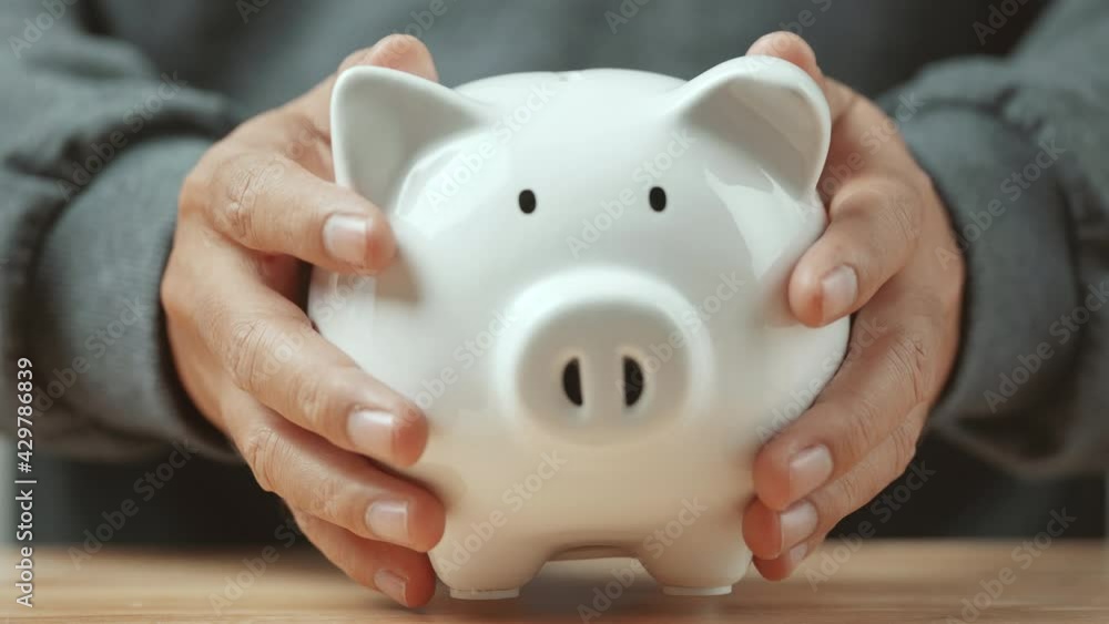 Man hand holding piggy bank on wood table. Save money and financial investment Man hand holding piggy bank on wood table. Save money and financial investment