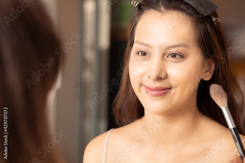 Free Download Young asian woman in bedroom. Make-up artist in beauty studio doing makeup for beautiful girl.Beautiful young master make-up artist applies powder brush to face.Woman Profile making up using pencil. - GFXLoad