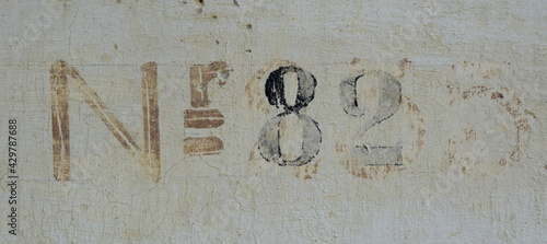 Hausnummer 82 auf einer alten Hausmauer mit Farbe aufgetragen in alter Schrift - braun, beige und schwarz