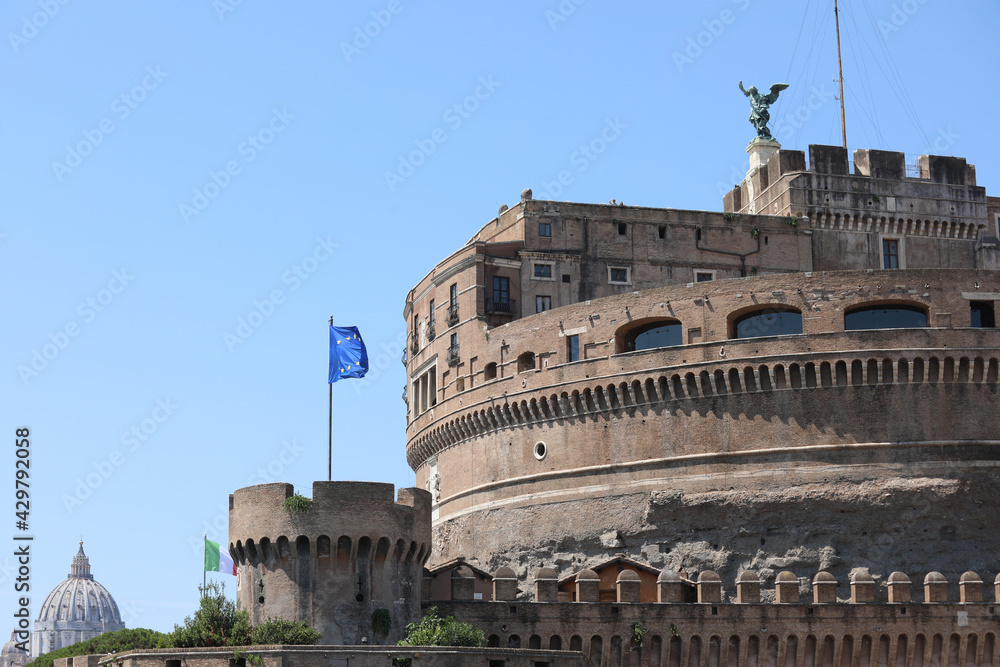Monument called Castel Sant'Angelo in Rome and the European flag flying in the background you can see the dome of St. Peter