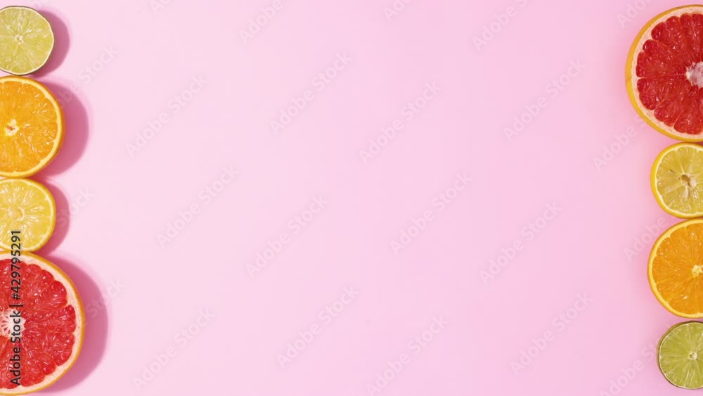 Sliced citrus orange grapefruit, lemon and lime move on left and right side on bright pink background. Stop motion flat lay Sliced citrus orange grapefruit, lemon and lime move on left and right side on bright pink background. Stop motion flat lay