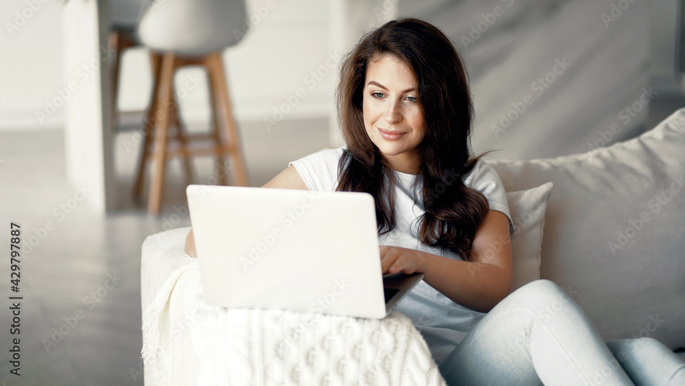 Makes online purchases on the computer. The housewife is sitting at home. Young woman online training on a laptop. Makes online purchases on the computer. The housewife is sitting at home. Young woman online training on a laptop.