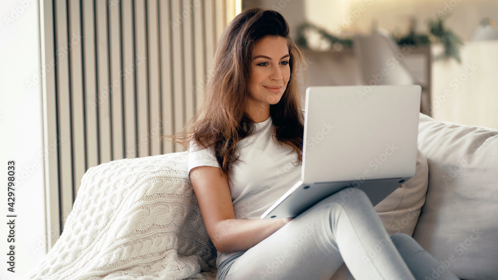 Young woman of European appearance online training on a laptop. Blogger housewife brunette sitting at home. Makes online purchases on the computer. Young woman of European appearance online training on a laptop. Blogger housewife brunette sitting at home. Makes online purchases on the computer.