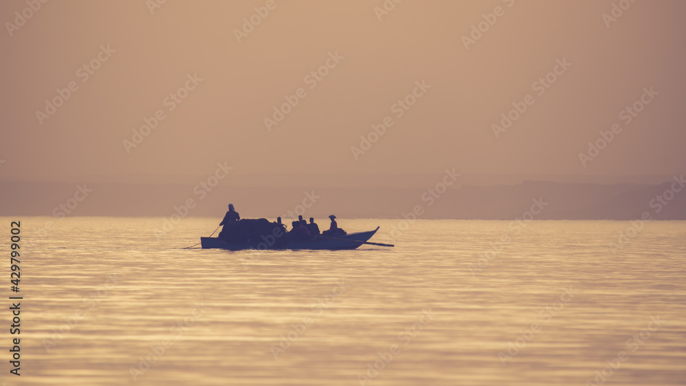 Fishermen on a boat in the sea at sunset
