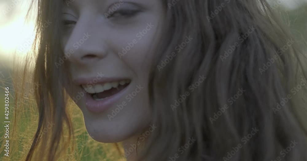 Close-up of brown hared girl with grey eyes spinning around. Filmed outdoors. Blurred background Close-up of brown hared girl with grey eyes spinning around. Filmed outdoors. Blurred background
