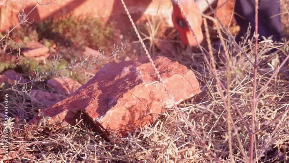 Young man with hammer in hands and braking stone,working with natural stone,laborer breaking rocks with a hammer on a sunny day Young man with hammer in hands and braking stone,working with natural stone,laborer breaking rocks with a hammer on a sunny day