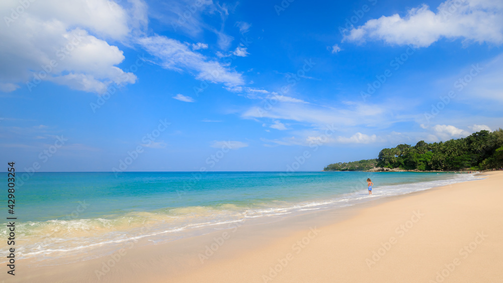 Beach and tropical sea with small travelling tourists and blue sky background summer holiday at Phuket Thailand