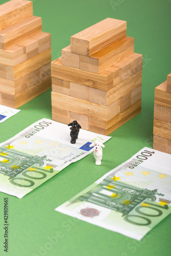 Three houses, three 100 euros banknotes and green background. Concept for real estate market