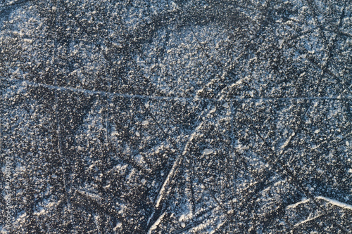 The texture of ice on a river or lake in winter with traces and stripes from the blades of skates