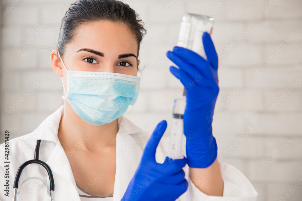 Portrait of the beautiful young nurse who is gaining medicine in a syringe indoors Portrait of the beautiful young nurse who is gaining medicine in a syringe indoors